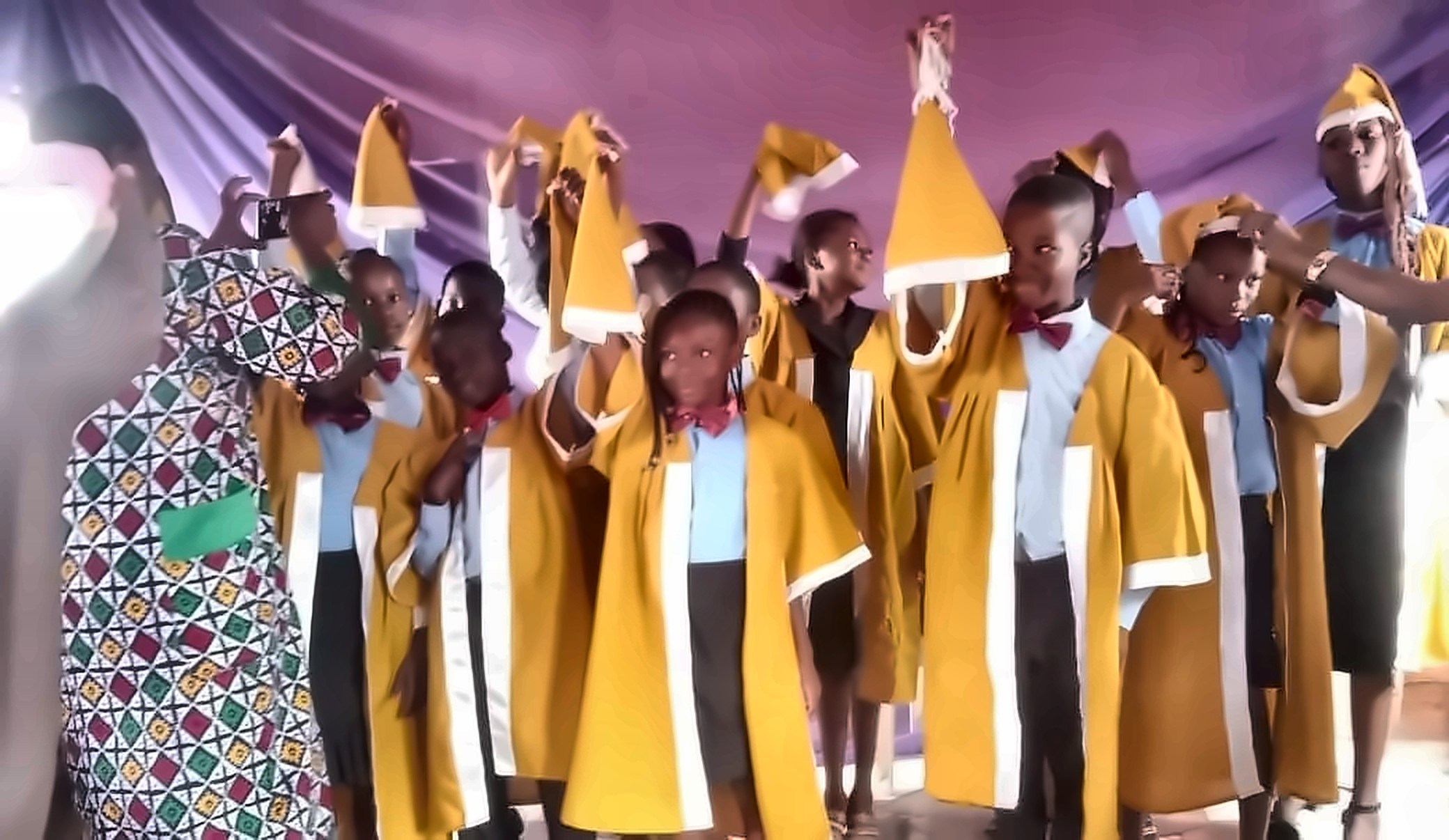 Graduating pupils in gold gowns tossing their caps