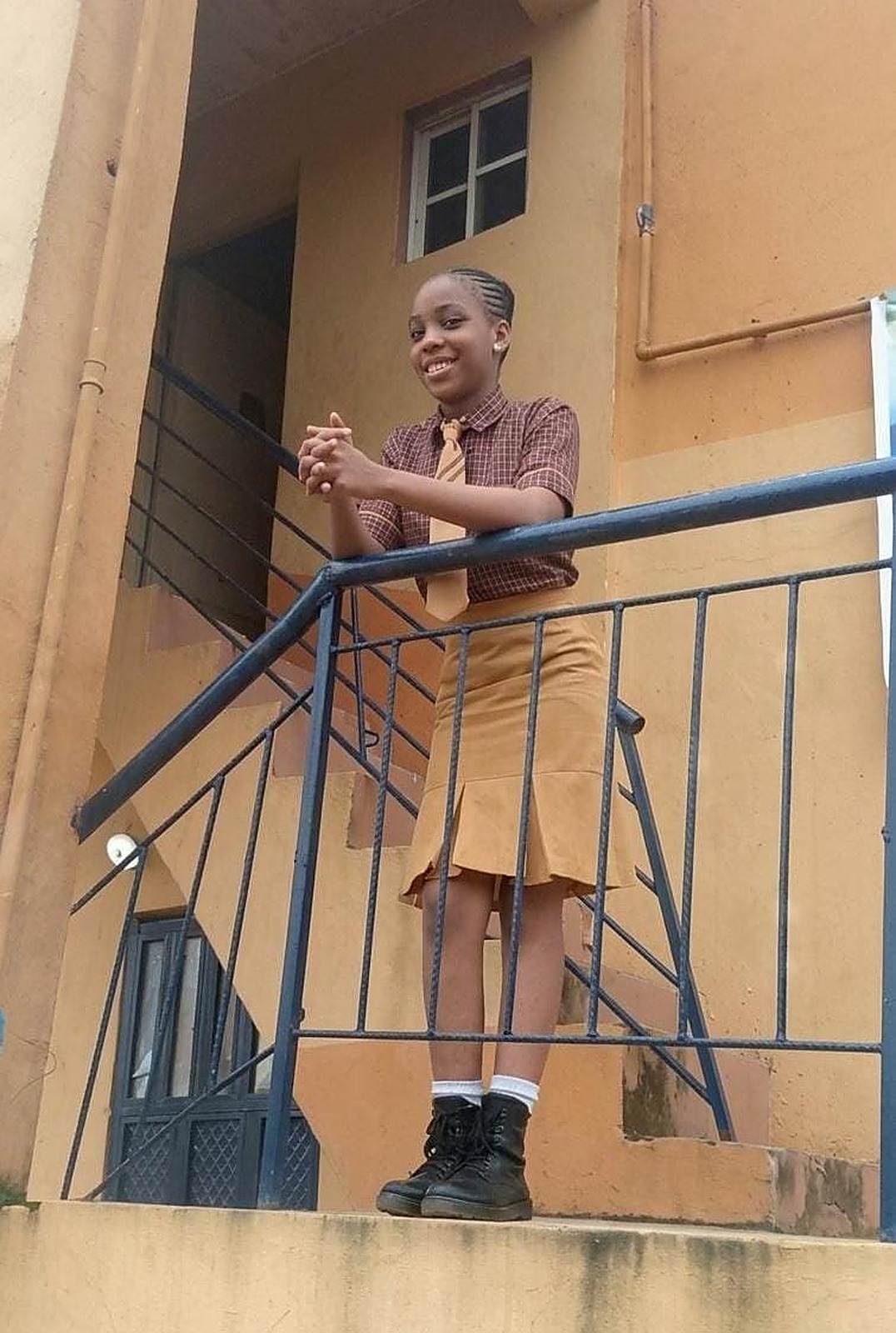 A smiling Success Private School pupil in uniform on the school stairs