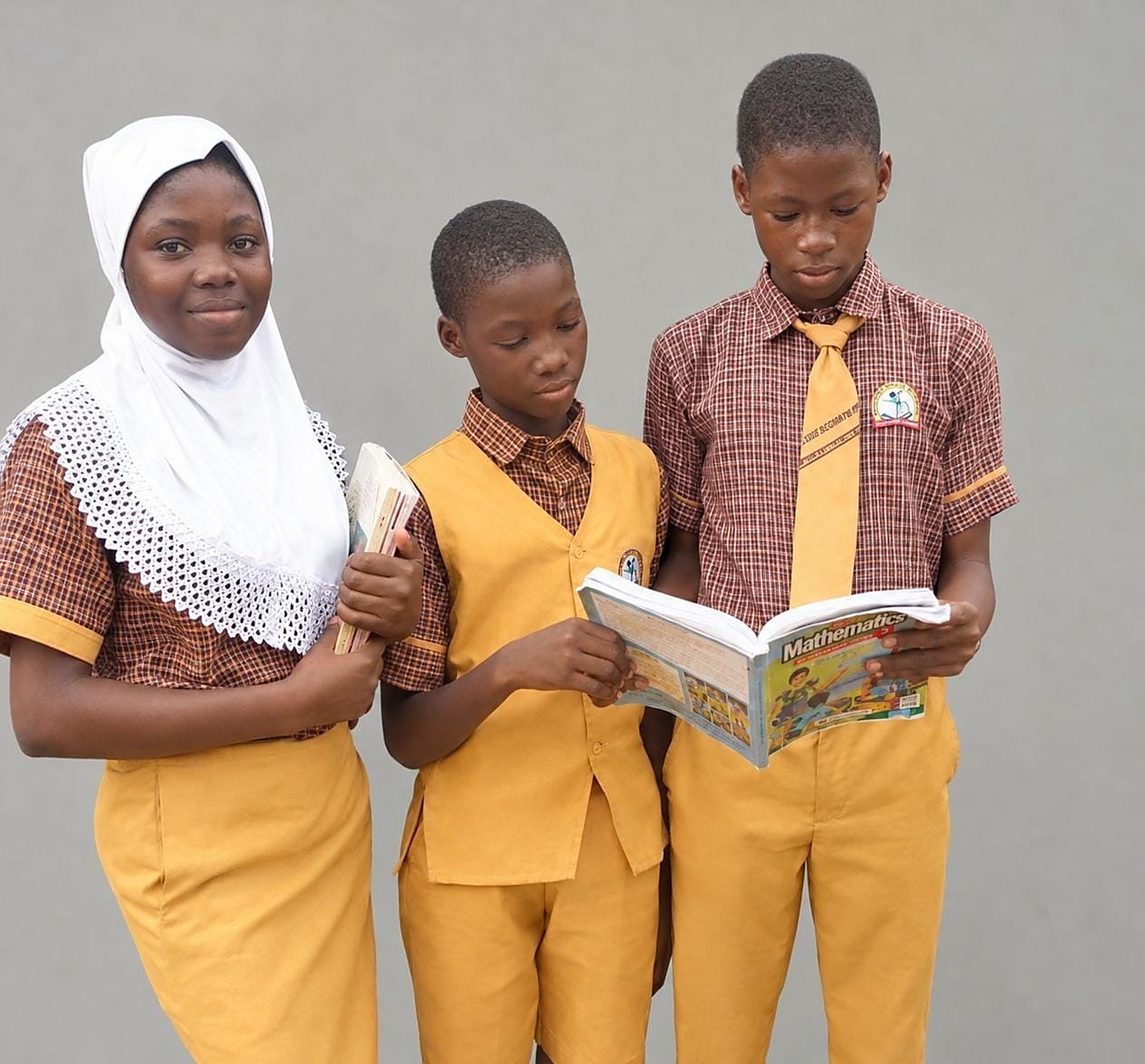 Three Success Private School pupils reading a Mathematics textbook together